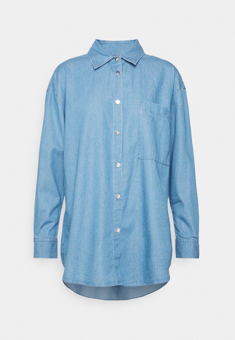 Chemise en denim bleu clair à manches longues avec col, fermeture à boutons-pression sur le devant, une poche poitrine et ourlet arrondi.