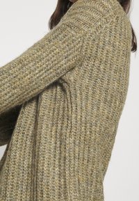 Strickjacke in gedämpften Grün- und Brauntönen mit einem strukturierten Muster, weit geschnittenen Ärmeln und einer lässigen Passform.