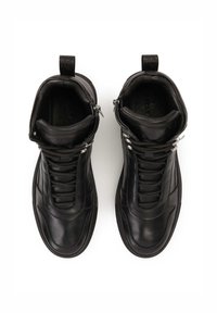 Zapatillas altas de cuero negro con cordones en la parte delantera, laterales con cremallera y tiradores, que presentan texturas suaves y un diseño minimalista.