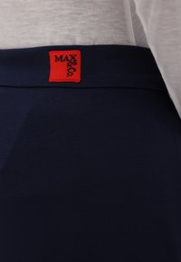 Navy elastic waistband with a small red rectangular tag featuring "MAX" in black text. Smooth, soft fabric texture. Close-up view.