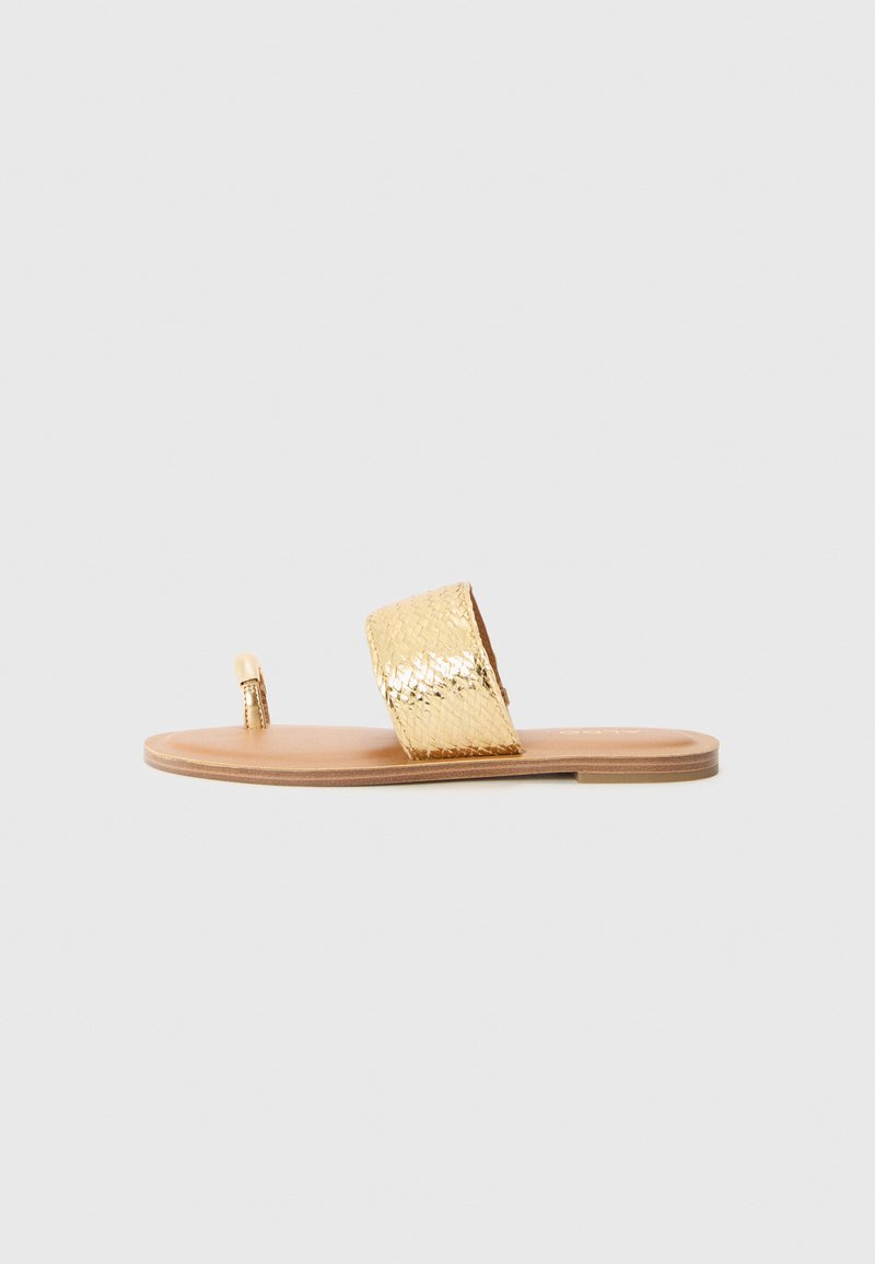 Zlaté kovové ploché sandály s texturovaným předním páskem, otevřenou špičkou a hladkou hnědou podešví. Ozdobené dekoračním páskem na prsty.