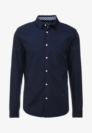 Marineblaue Langarmbluse mit einem Button-Down-Kragen, kontrastierendem kariertem Innenkragen und weißen Knöpfen auf der Vorderseite. Glatte Textur.