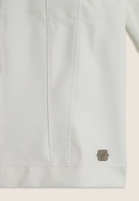 Chemise blanche à manches longues avec une texture lisse, dotée de coutures décoratives, de deux poches poitrine et d'un accent de logo en métal au bas.