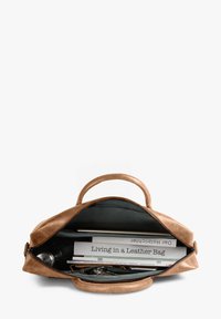 Tan leather bag with a zipper, featuring a spacious interior containing books, documents, and personal items. Smooth texture and sturdy handles.