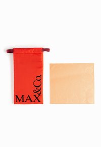 Bolsa de tela roja con cordón y el logo negro "MAX & Co.", junto a un cuadrado de color naranja claro con un diseño de texto en relieve.