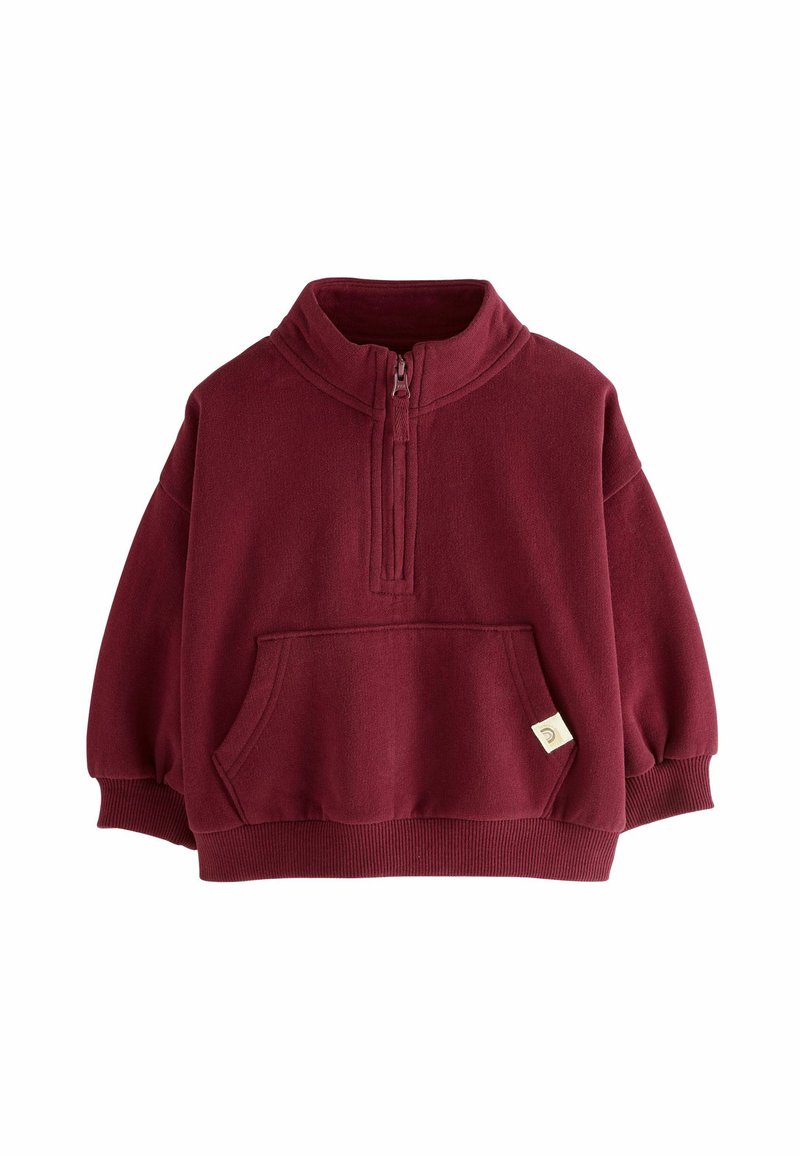 Pullover in pile bordeaux con mezza zip, polsini a coste, tasca frontale e un piccolo cartellino. Texture morbida e vestibilità ampia. Ideale per un abbigliamento casual.