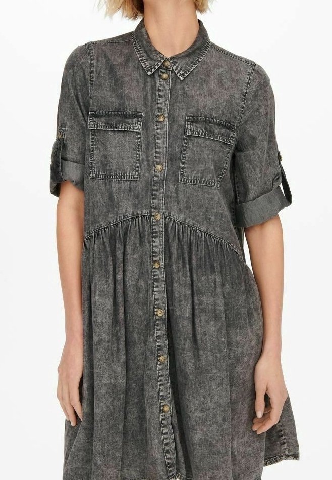 Farkkumekko haalistuneessa mustassa, jossa on paitakaulus, lyhyet käännetyt hihat, kaksi etutaskua ja laskostettu hameosa, napilliset suljettavat yksityiskohdat.