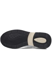 Zwarte rubberen schoenzool met een patroon op de loopzijde, voorzien van een crèmekleurige tussenzool en tekstdetails. Flexibel ontwerp met verschillende getextureerde groeven.