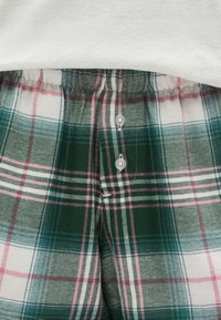 Πράσινο και λευκό καρό πιτζάμα παντελόνι με απαλή υφή, ελαστική μέση και δύο λευκά κουμπιά στο μπροστινό μέρος.