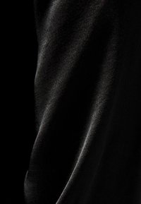 Svart satin tyg med en mjuk textur som visar en lätt glans och mjuk fall med subtila ljusreflektioner över ytan.