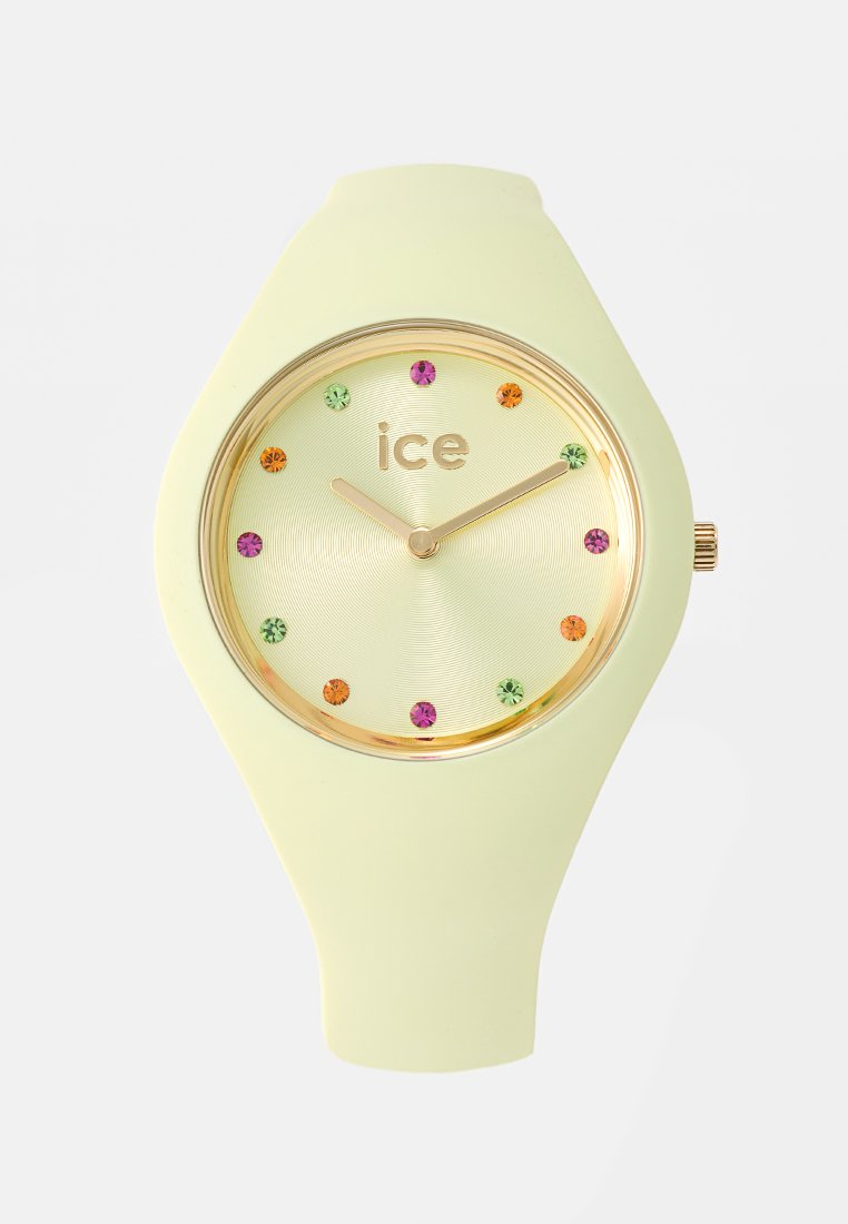 Montre en silicone vert clair avec un cadran rond doré, présentant une surface texturée et des marqueurs d'heure en cristal colorés.