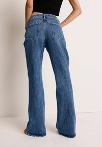 Lyseblå vid-berede jeans lavet af denim, med store baglommer, høj talje og råkant detaljer ved anklerne.