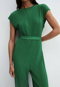 Mono verde con pliegues, de mangas cortas, cintura ajustada, textura lisa y diseño fluido. Estilo minimalista y construcción sin costuras.