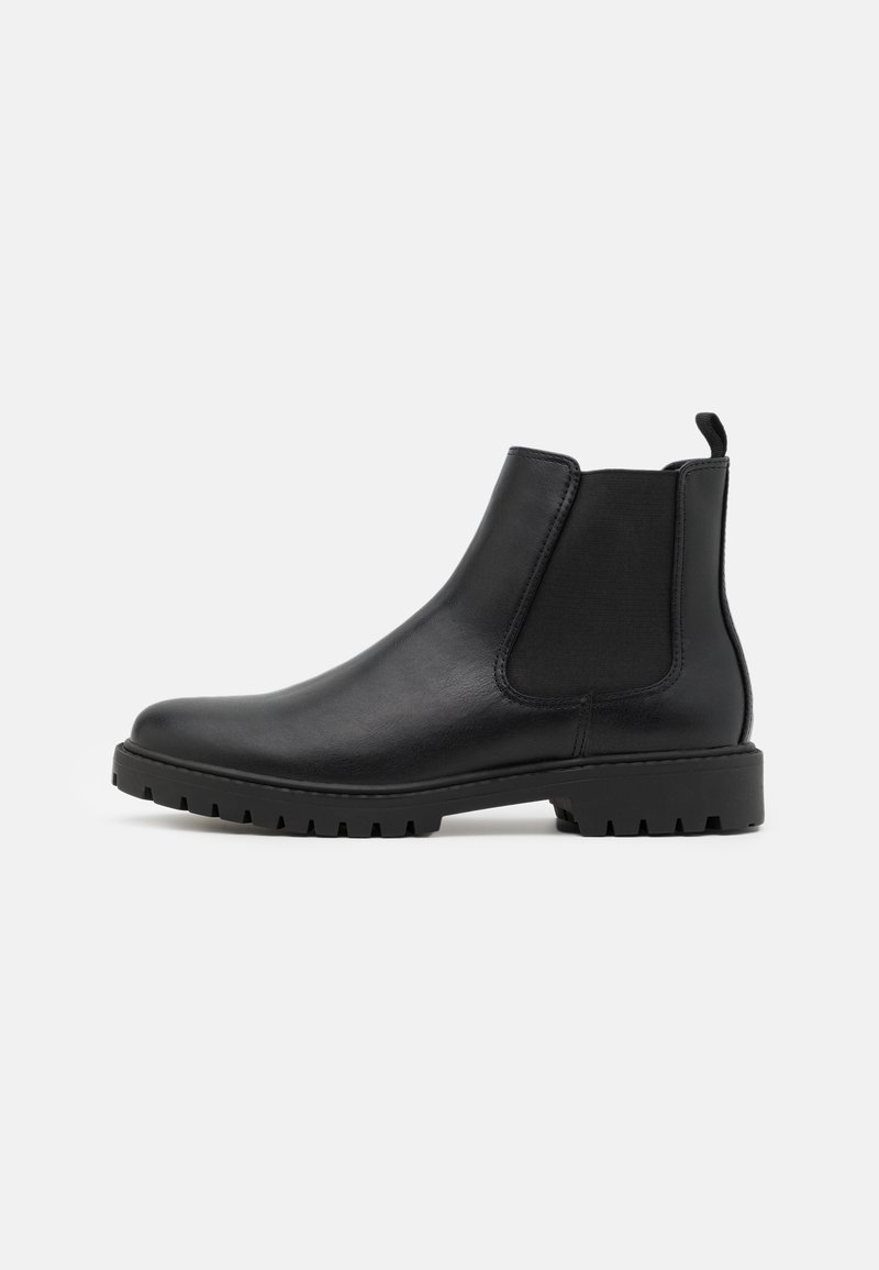 Botte Chelsea en cuir noir avec empiècement latéral élastique, languette au talon et semelle épaisse en caoutchouc clouté, présentée en profil droit.