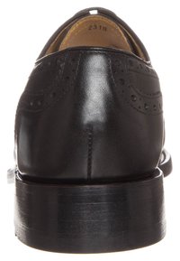 Sorte læder dresssko med brogue-detaljer, med en rund tå og en stablet hæl. Overdelen har glatte og strukturerede overflader.