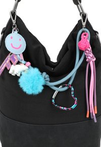 Sac noir avec des porte-clés colorés, y compris un smiley rose, un ours polaire, un pompon bleu, un mousqueton en forme de cœur et des nœuds décoratifs en corde.