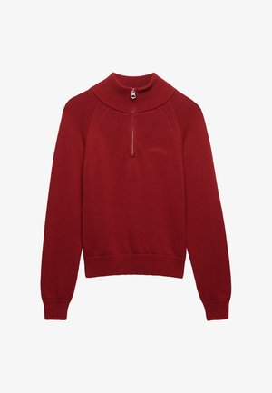 Rød strikket pullover med høj krave, halvlange lynlåsdetalje, ribstrikkede manchetter og kant, med et diskret logo på brystet og teksturerede syninger.