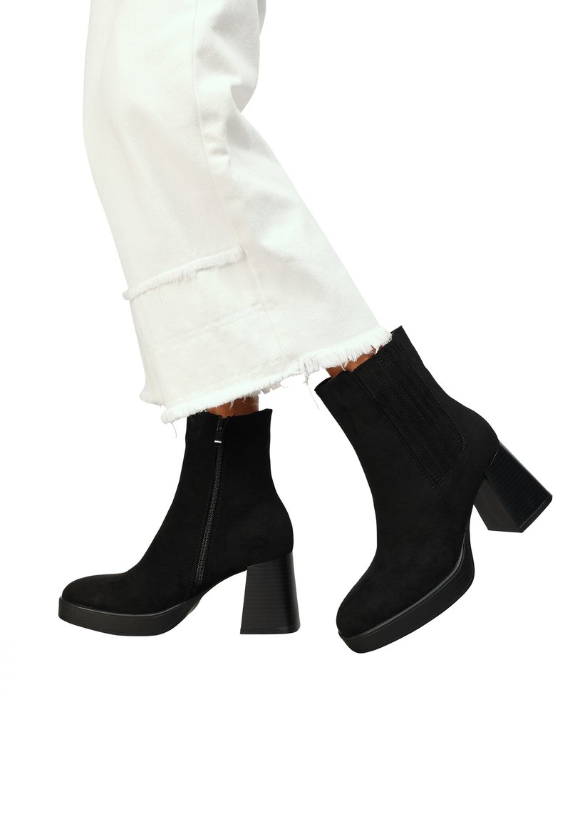 Bottines en daim noir avec une fermeture éclair latérale et des détails côtelés, dotées d'un talon épais et texturé et d'un design épuré et élégant.