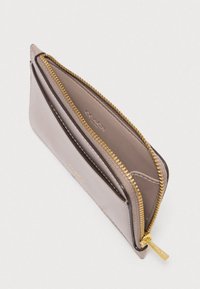 Plāns taupe ādas maks ar daļēji atvērtu zelta rāvējslēdzēju, ārēju karšu nodalījumu un uzspiestu Coach zīmola nosaukumu uz rāvējslēdzēja piespraudes.