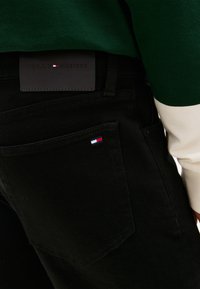 Μαύρο τζιν από denim με πατς λογότυπο Tommy Hilfiger στην πλάτη, που διαθέτει ένα μικρό τρίχρωμο έμβλημα στην τσέπη και εφαρμοστή σχεδίαση.