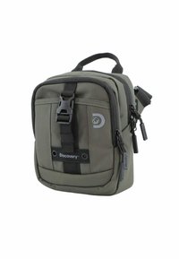 Bolso bandolera de tela verde con forma rectangular, que cuenta con un asa superior, correa ajustable y compartimentos con cremallera. Logo de la marca visible.