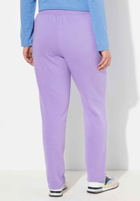 Lila skjortsbyxor med elastisk midja, rak bendesign och mjukt material, i kombination med avslappnade, flerfärgade sneakers.