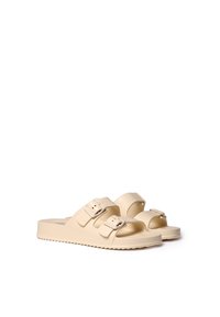 Beige slaidu sandales, kas izgatavotas no mīksta materiāla, ar divām regulējamām siksnām ar tapu sprādzēm, kontūrveida zoli un teksturētu pamatu.