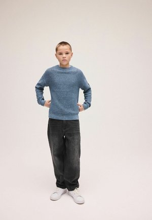 Blue textured knit sweater with a crew neckline, paired with loose-fitting dark gray jeans and white sneakers.