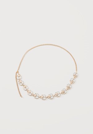Collier chaîne en or avec des grappes de fleurs en pierre blanche disposées uniformément le long de la moitié inférieure de la chaîne sur fond blanc.