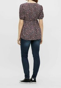 Blusa con stampa floreale e maniche puff corte, vita elastica e vestibilità rilassata, abbinata a jeans scuri slim e sneakers nere in tela.