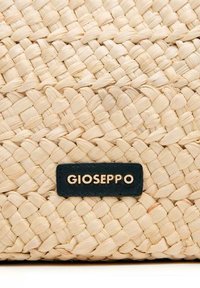 Bolsa de fibra natural tejida con un patrón texturizado en color crema. Presenta una etiqueta de cuero negro con el texto en relieve dorado "GIOSEPPO."