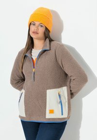 Brauner Fleece-Pullover mit einem Viertel-Reißverschluss, cremefarbenen Taschen, blauen Reißverschlüssen und einer orangen Mütze. Verfügt über eine weiche Textur und markante Farbakzente.
