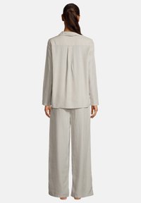 Ljust grå, långärmad pyjamas-set med en skjorta med krage och ett bakfåll, tillsammans med vida byxor, båda i mjukt tyg.