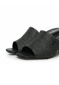 Scarpe slip-on nere intrecciate con punta aperta e tacco basso e spesso, presentano suole nere lisce e un discreto dettaglio del logo.