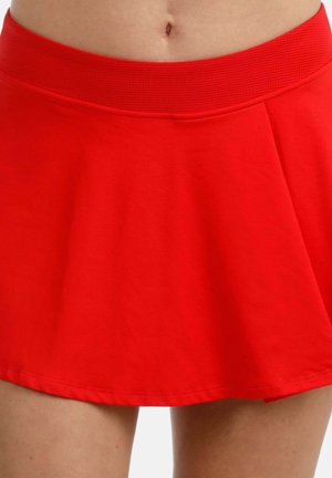 Roter ausgestellter Rock mit breitem geripptem Bund, getragen am unteren Oberkörper und an den oberen Oberschenkeln, zeigt den freien Bauch und die Beine.