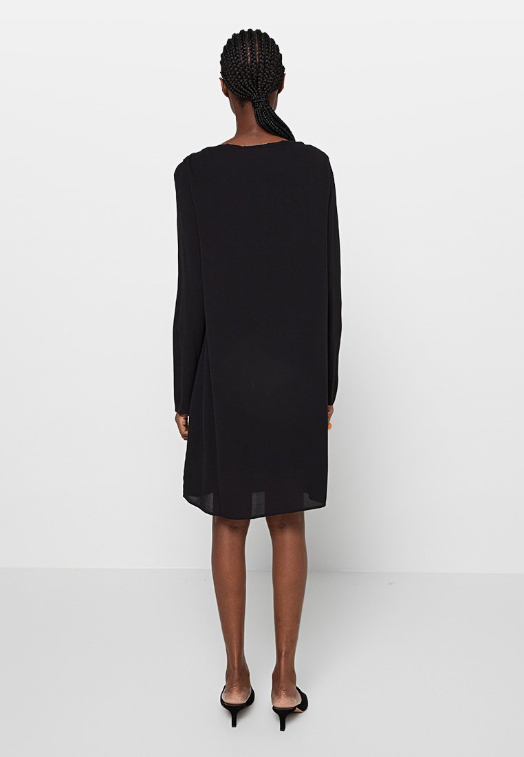 Abito nero a maniche lunghe realizzato in tessuto leggero, con una vestibilità morbida, orlo arrotondato e un design minimalista.