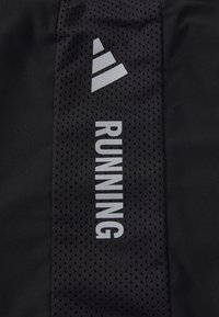 Schwarzer Stoff mit vertikalem Netzstreifen, auf dem das Wort "RUNNING" und ein dreistreifiges Dreieck-Logo in hellgrau zu sehen sind.