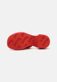 Pala de sapato em borracha vermelha com padrão texturizado do logótipo "CAMPER". A seção do calcanhar circular, rotulada com o tamanho 35, apresenta letras em relevo em negrito.