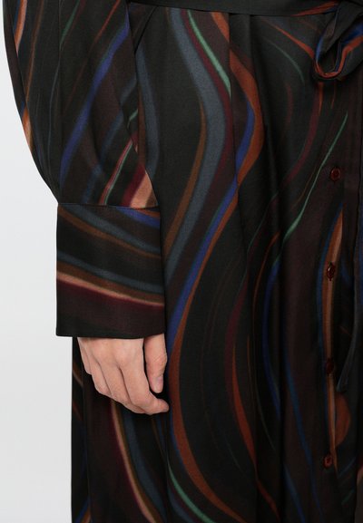 Camicia a maniche lunghe con bottoni, dal design fluido in tessuto nero, caratterizzata da linee ondulate colorate in tonalità di rosso, verde, blu e marrone.