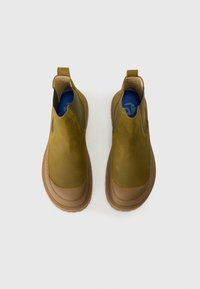 Olive zelene slip-on čevlje z rjavim gumijastim podplatom, z gladkim usnjenim zgornjim delom in elastičnimi stranskimi paneli za enostavno obuvanje.
