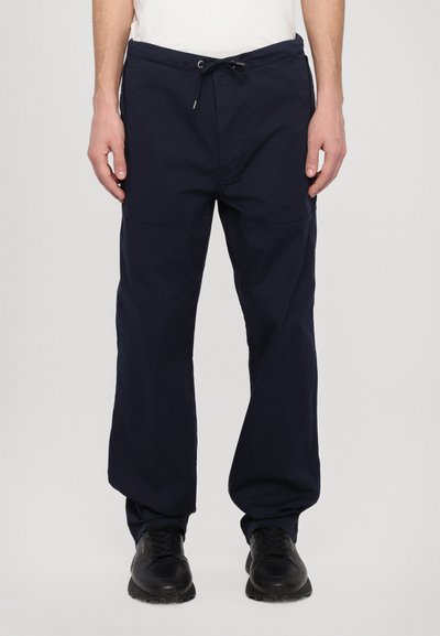 Pantalons en coton bleu marine avec taille élastique à cordon, jambe fuselée et deux poches avant. Tissu texturé, design décontracté adapté à un usage quotidien.