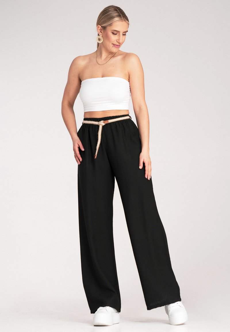Czarne spodnie z szerokimi nogawkami i elastycznym pasem, ozdobione paskiem w stylu sznura z skórzanym akcentem, połączone z białym topem bez ramiączek.