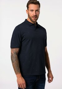 Camisa polo marina de manga corta, con un patrón sutil de pequeños motivos, confeccionada en un tejido suave y con un diseño de cuello clásico.