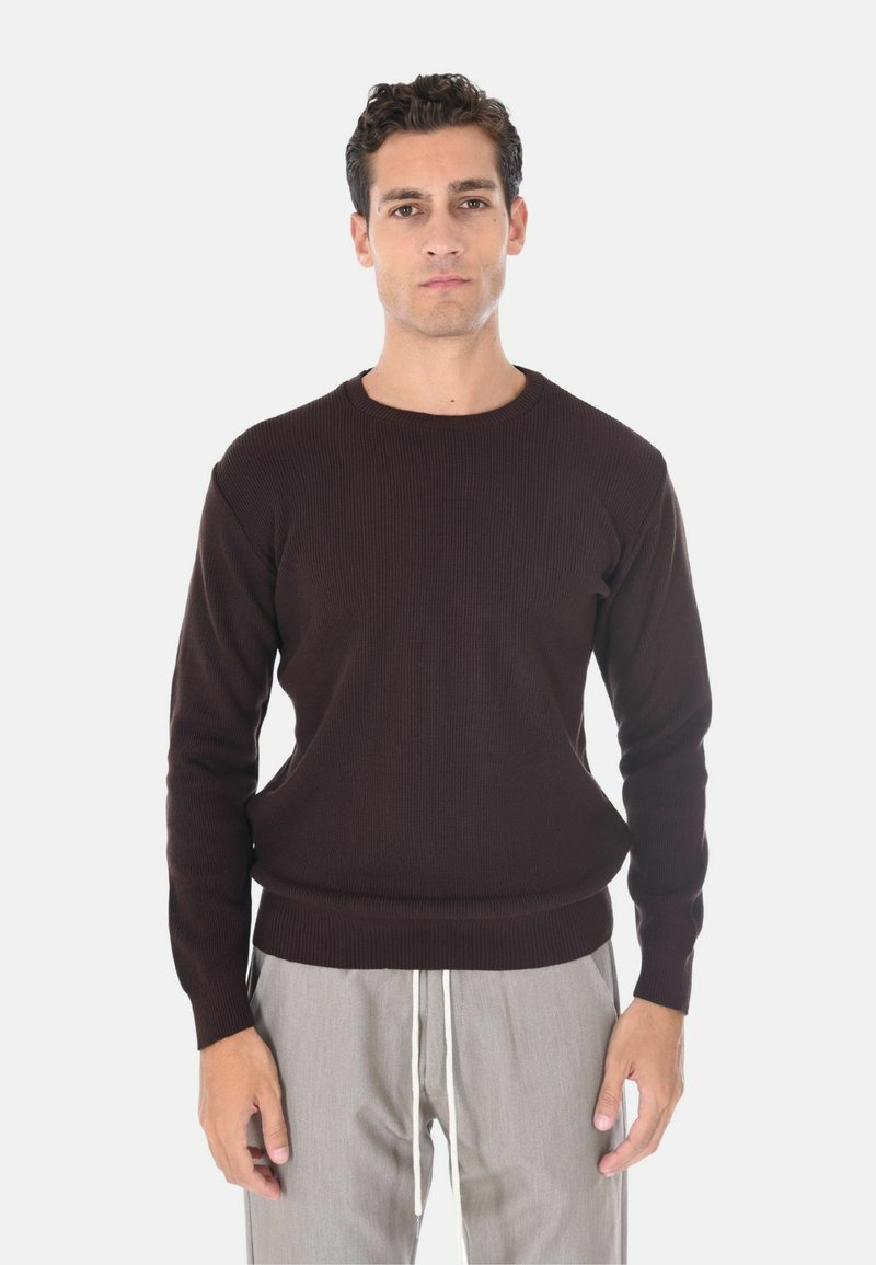 Maglione a coste marrone scuro con scollatura tonda e maniche lunghe, abbinato a pantaloni grigi chiari con cordoncino.