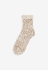 Helle beigefarbene Flauschsocke mit einer weichen Textur, einem umgeschlagenen Saum und einem leicht helleren, gesprenkelten Muster im gesamten Körper.