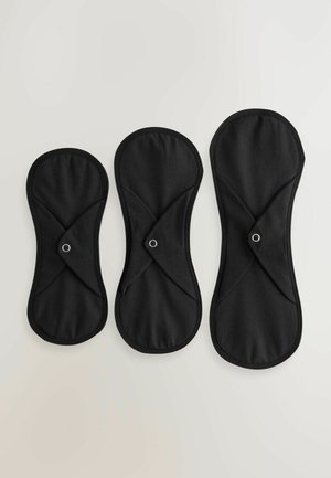 Trois serviettes hygiéniques réutilisables en tissu noir de tailles différentes. Chacune présente une forme ovale avec un tissu croisé et une fermeture à pression.