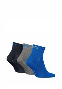 Tres pares de calcetines hasta el tobillo en azul marino, gris y azul, que presentan un puño acanalado y un logotipo blanco en contraste en la parte superior.
