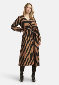 Lange wikkeljurk met een bruin en zwart zebrapatroon. Kenmerkt lange mouwen, een strik taille en een vloeiende silhouet. Glad textuur van de stof.