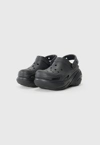 Black plastic clogs with perforated sides, thick soles, and a back strap for support. Smooth texture and rounded toe design.