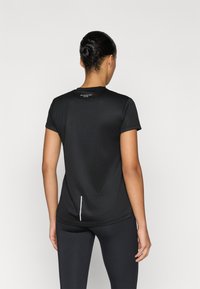 Schwarzes Sport-T-Shirt aus strukturiertem Stoff, mit kurzen Ärmeln, rundem Halsausschnitt und einem reflektierenden Akzent auf der Rückseite.